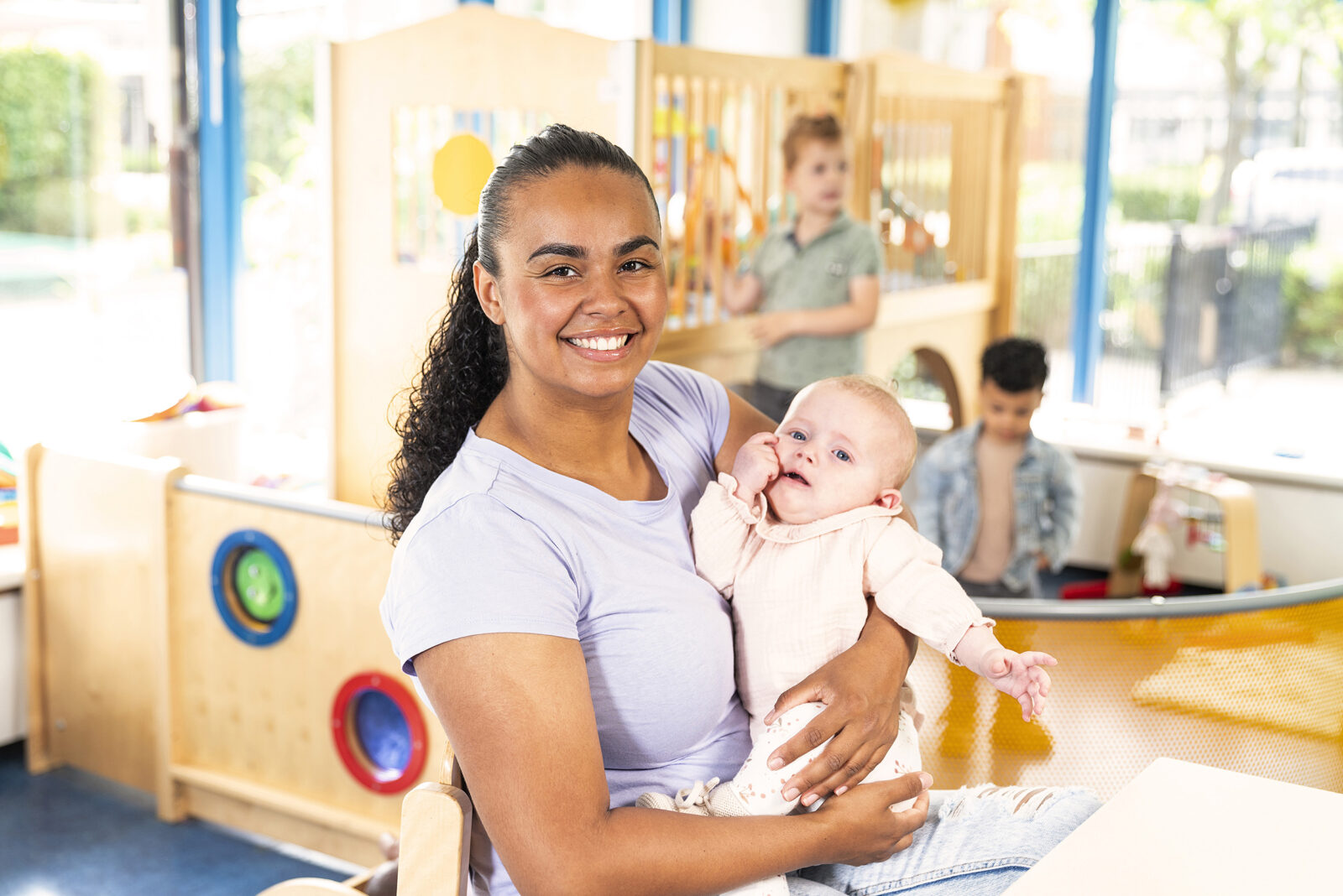 Pedagogisch medewerker in het beeld met een baby op onze kinderopvanglocatie